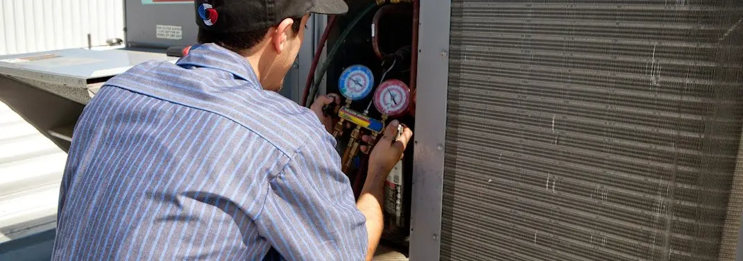 HVAC technician servicing a condenser unit in Port Angeles
